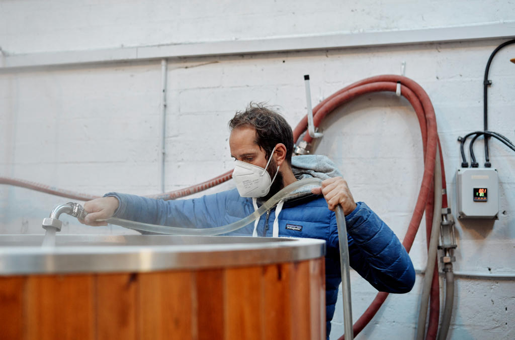 Gareth at Dynamite Valley Brewing Co. transferring hot water into the tun for mixing
